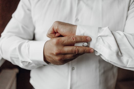 A man is getting dressed in a white shirt and is adjusting his cuff. Concept of formality and attention to detail, as the man takes care to properly dress himself photo