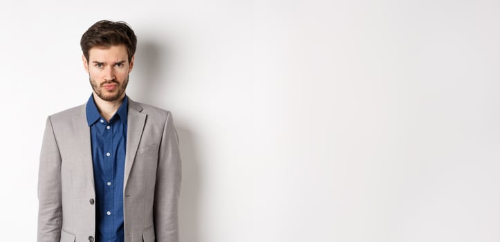 Sad offended guy sulking, wearing business suit, feel something unfair, standing childish against white background photo