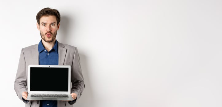 Handsome caucasian businessman in suit showing empty laptop screen, demonstrate promo, standing on white background photo