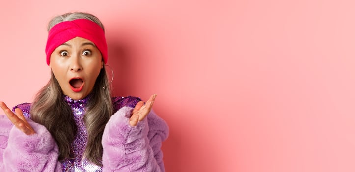 Fashion. Close-up of fashionable asian elderly woman reacting to special offer, scream and gasping surprised at camera, standing over pink background photo