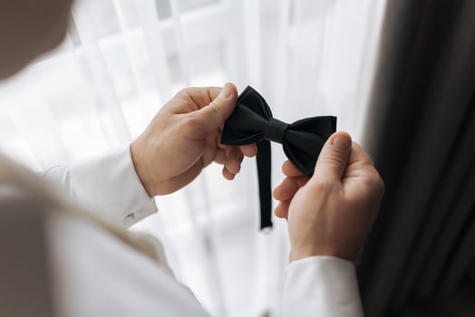 A man is getting ready to tie his bow tie. He is holding the tie in his hands and adjusting it. Concept of preparation and attention to detail photo