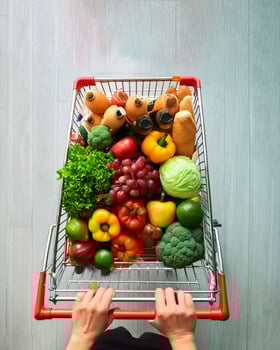 Woman pushing a shopping cart full of fresh delicious vegetables and fruits, grocery shoppin photo