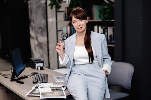 Businesswoman in blue suit leans on desk in modern office photo