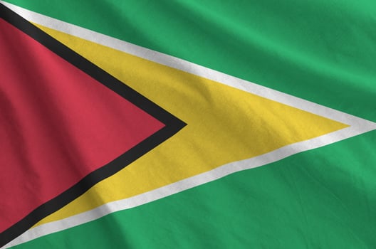 Guyana flag depicted on folded wavy fabric of old cloth photo
