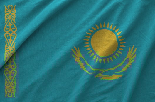 Kazakhstan flag depicted on folded wavy fabric of old cloth photo