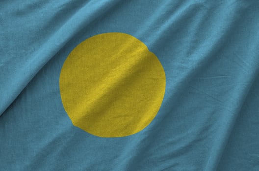 Palau flag depicted on folded wavy fabric of old cloth photo
