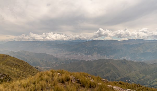a mountain range with yellow grass, distant mountains and forests with cloudy sky in the background photo