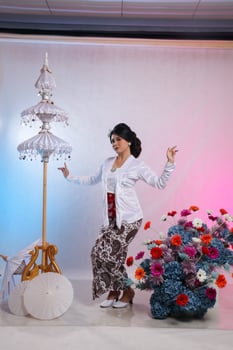 Full body of adult Asian woman standing dancing wearing modern Javanese traditional clothing, white velvet bridal kebaya on a white studio background. for advertising content, romance, beauty, fashion photo