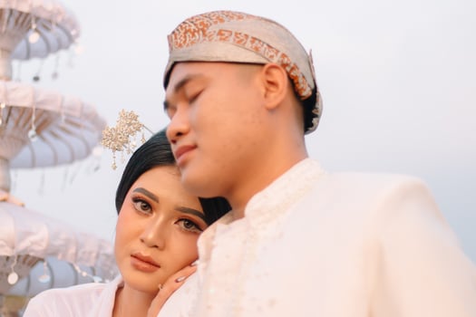A pair of young Asian boy and girl lovers standing, the man sleeping on the woman's shoulders wearing modern Javanese traditional clothing, the bride's white velvet kebaya. beauty, fashion photo