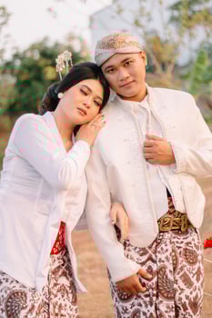 A pair of young Asian male and female lovers standing, the woman sleeping on the man's shoulder wearing modern Javanese traditional clothing. for advertising content, romance, beauty, fashion photo
