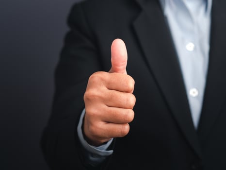 Businessman showing thumbs up like hand sign gesture against a gray color background. Happy confident man gesture. Space for text. Success in business photo
