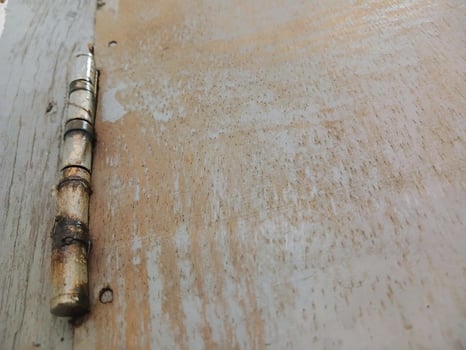 Rusty door hinges cut into the wooden door, connecting fasteners screwed in, construction parts. photo