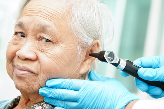 Otolaryngologist or ENT physician doctor examining senior patient ear with otoscope, hearing loss problem. photo