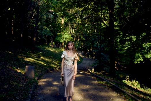 beautiful teenage girl in a silk skirt and a corset in the old money style walks in the park and along the river bank photo