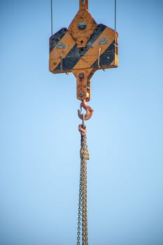 A close-up shot of a crane hook lifting heavy chains, showcasing industrial strength and precision. Perfect for construction, engineering, and heavy machinery themes. photo