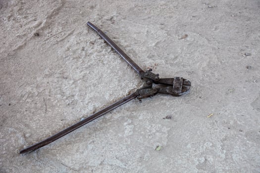 A close-up of a rebar cutter on a construction site floor, showcasing its sharp blades and rugged design, ready for heavy-duty metal cutting tasks. photo