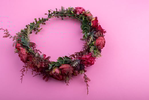Colorful artificial flowers wreath isolated on pastel pink background photo