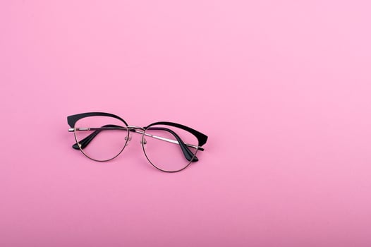 Black frame eyeglasses isolated on pastel pink color background photo