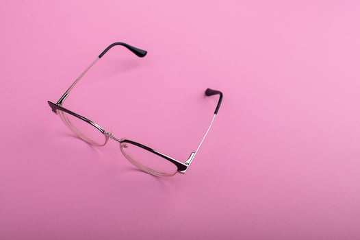 Black frame eyeglasses isolated on pastel pink color background photo