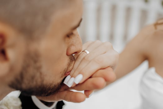 A man kisses a woman's hand, both wearing wedding rings. Concept of love and affection between the couple, as they share a tender moment together photo