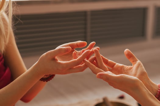 The hands of two women are intertwined into a castle, engaged in energy practice photo
