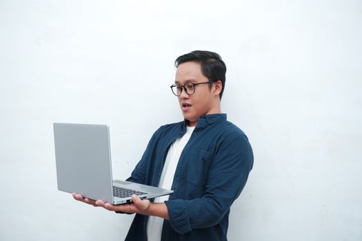 Asian man with blue shirt holding a laptop and smiling to camera. Concept of student or business man. isolated on white background photo