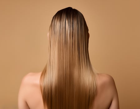 Young woman applying hair mask on beige background, back view photo