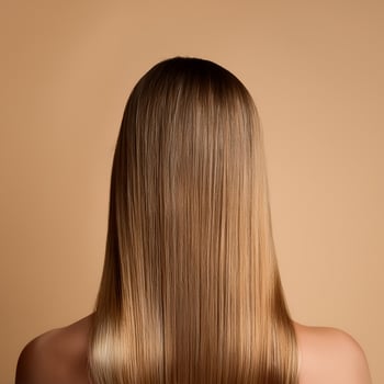 Young woman applying hair mask on beige background, back view photo