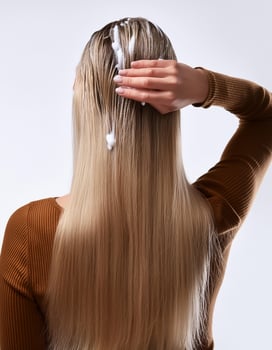 Young woman applying hair shampoo on white background, back view. photo