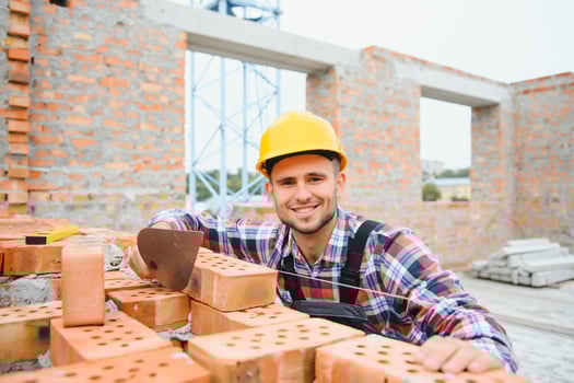 Yellow colored hard hat. Young man working in uniform at construction at daytime. photo