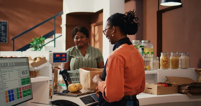 Local vendor scanning and weighting products for client, buying bulk products and vegetables. African american buyer and merchant talking about vegan nutrition and healthy lifestyle. Handheld shot. photo