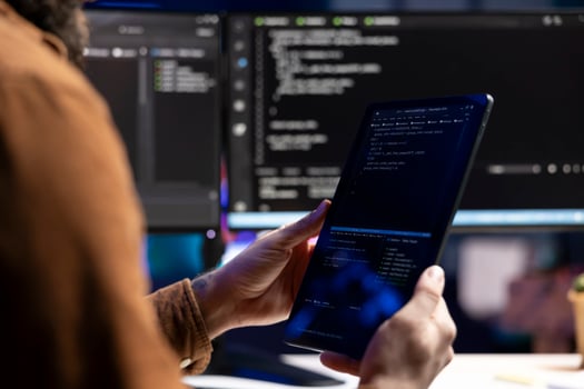 Computer scientist doing software quality assurance using tablet, reading source code before implementing it. Developer inspecting coding on portable device, looking to fix potential issues photo