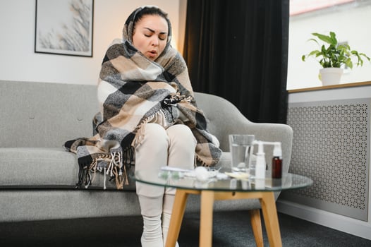 Sick Woman.Flu.Woman Caught Cold. Sneezing into Tissue. Headache. Virus .Medicines. Sick woman with a headache sitting on a sofa. photo