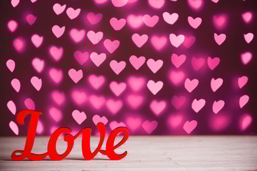 the inscription Love on a wooden background with beautiful hearts made of lights on a blurred background photo
