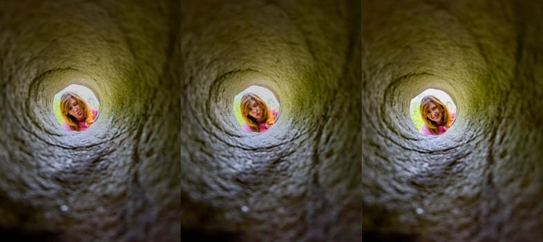 A young girl peers down a hole in granite, her face framed by the rugged stone. Her curious expression and the unique perspective create an engaging and playful scene, perfect for illustrating curiosity, exploration, and childhood adventures. photo