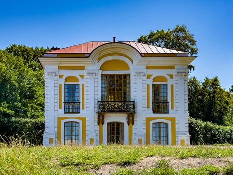 Charming view of an elegant historic pavilion with intricate architectural details, surrounded by lush greenery and clear blue skies, highlighting the beauty and serenity of the garden landscape photo