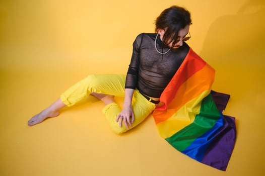 gay man with a gay pride flag smiling and looking away on yellow background photo