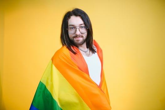 Gay man hold rainbow striped flag isolated on colored background studio portrait. People lifestyle fashion lgbtq concept photo