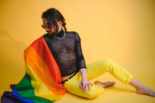 gay man with a gay pride flag smiling and looking away on yellow background photo