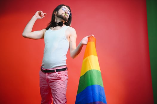 Gay man hold rainbow striped flag isolated on colored background studio portrait. People lifestyle fashion lgbtq concept photo