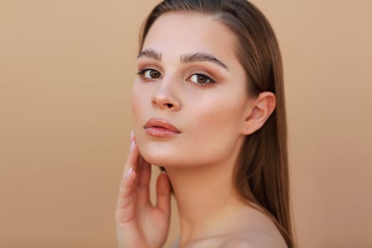 Beautiful Young Woman with Clean Fresh Skin touching own face. Facial treatment photo