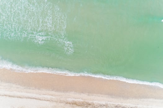 waves on the shore of a turquoise waters beach in the summer, aerial overhead view with drone photo