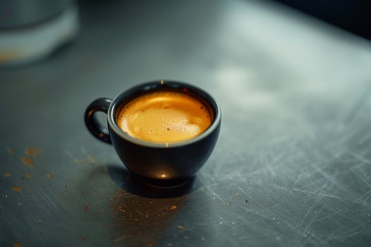 A black cup of espresso sitting on a table, background photo