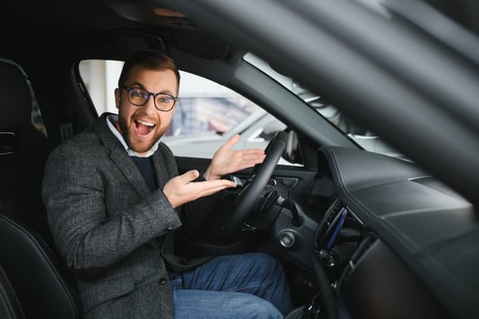 Visiting car dealership. Handsome bearded man is stroking his new car and smiling photo