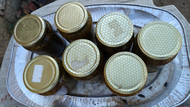 A tray with glass jars of flavored honey waiting to be filtered. photo