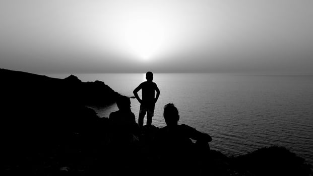 the silhouette of three people on the high coast during a sunset. photo