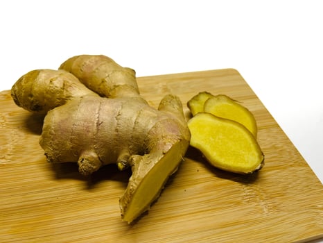 Ginger root with sliced on wooden cutting board on white background photo