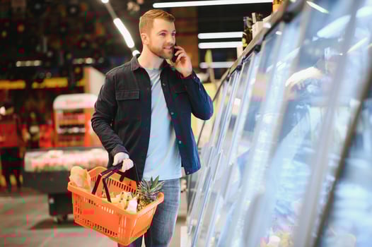 Young man buying groceries at the supermarket. Other customers in background. Consumerism concept. photo