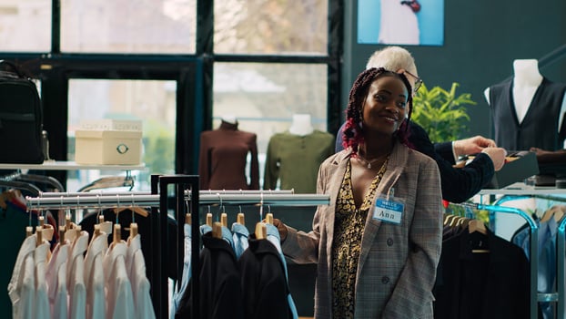 African american woman searching for comfortable pregnancy clothes, entering fashion boutique to look for items on clearance section. Pregnant client shopping for fashionable designs. Camera A. photo