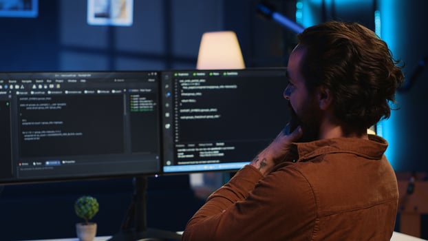 Happy self employed developer in home office doing coding on computer at desk. Joyful IT specialist doing contracted job from apartment, writing lines of code at workstation, camera A photo